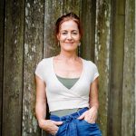 photo of woman standing against a wall, smiling