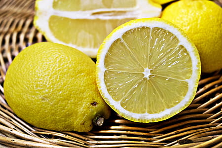 Three lemons, one cut in half, in a wicker basket